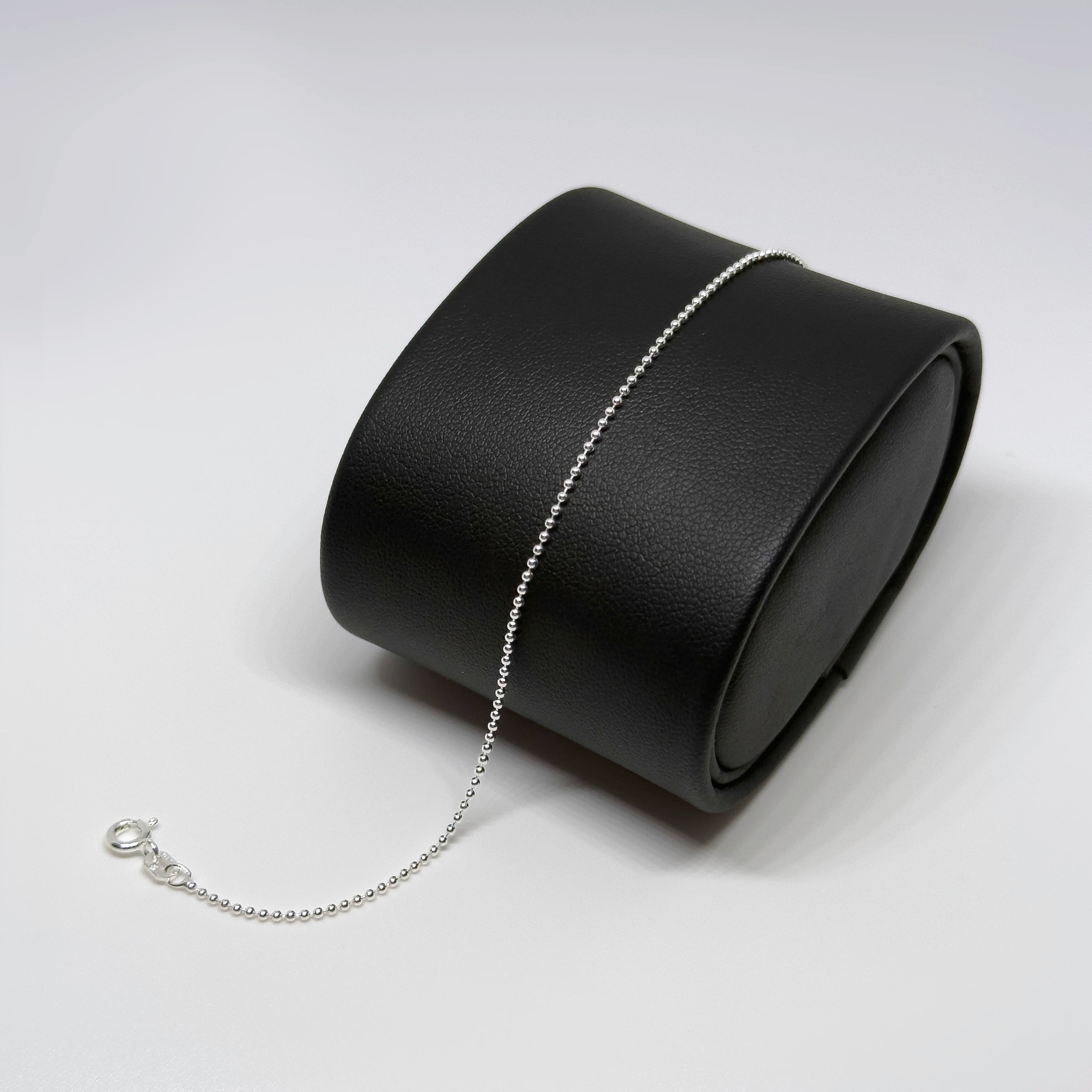 Hopeinen pallonilkkakoru kuvattuna mustalla korutelineellä