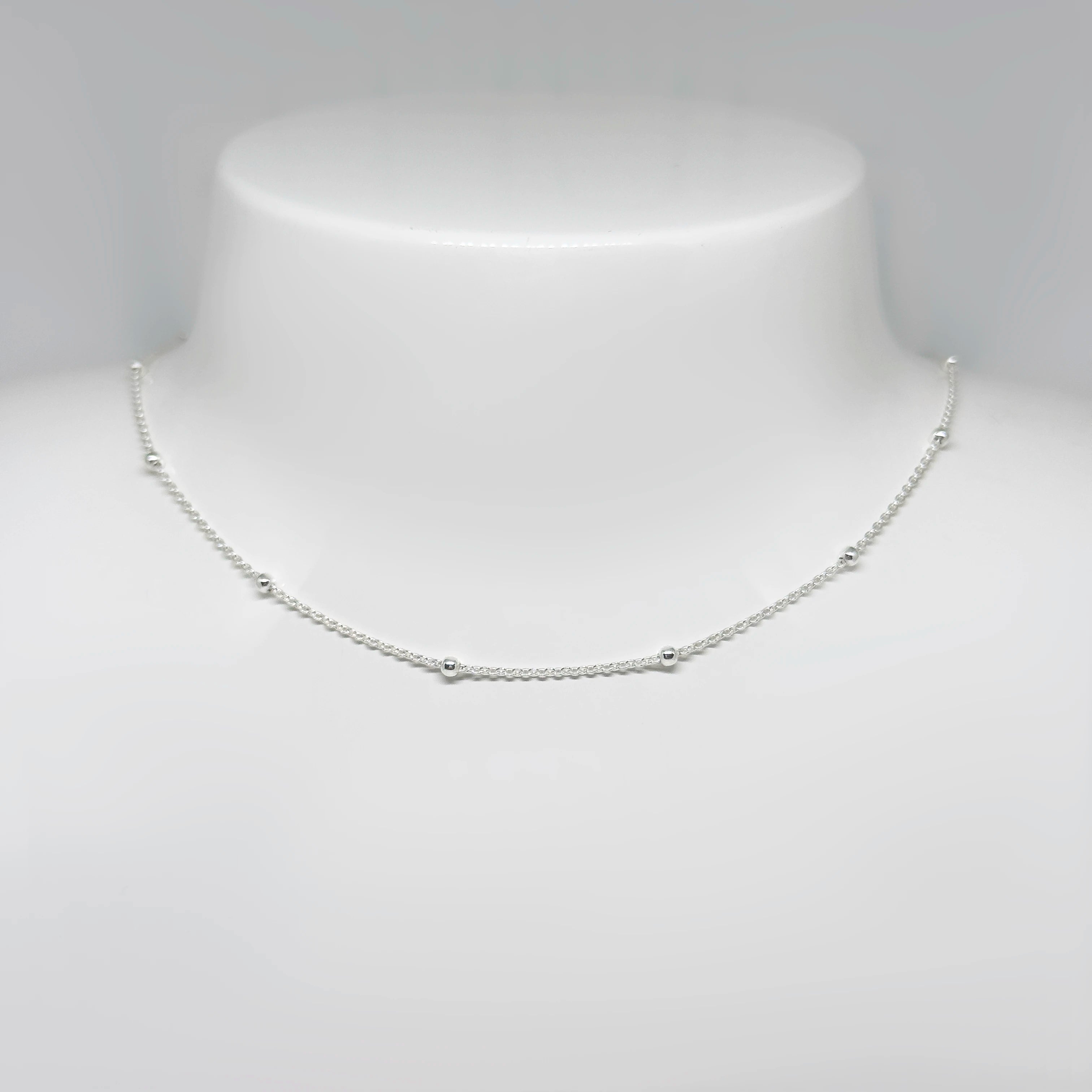 Hopeinen palloketju kuvattuna valkoisella korutelineellä