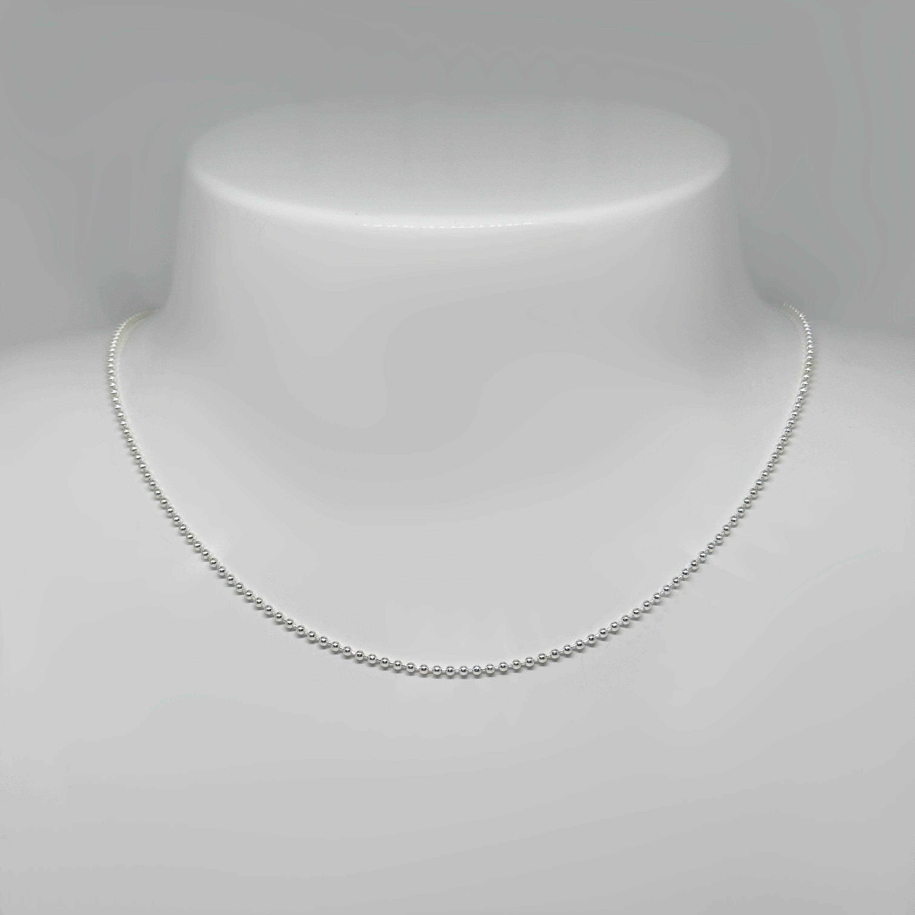 Hopeinen palloketju kuvattuna valkoisella korutelineellä