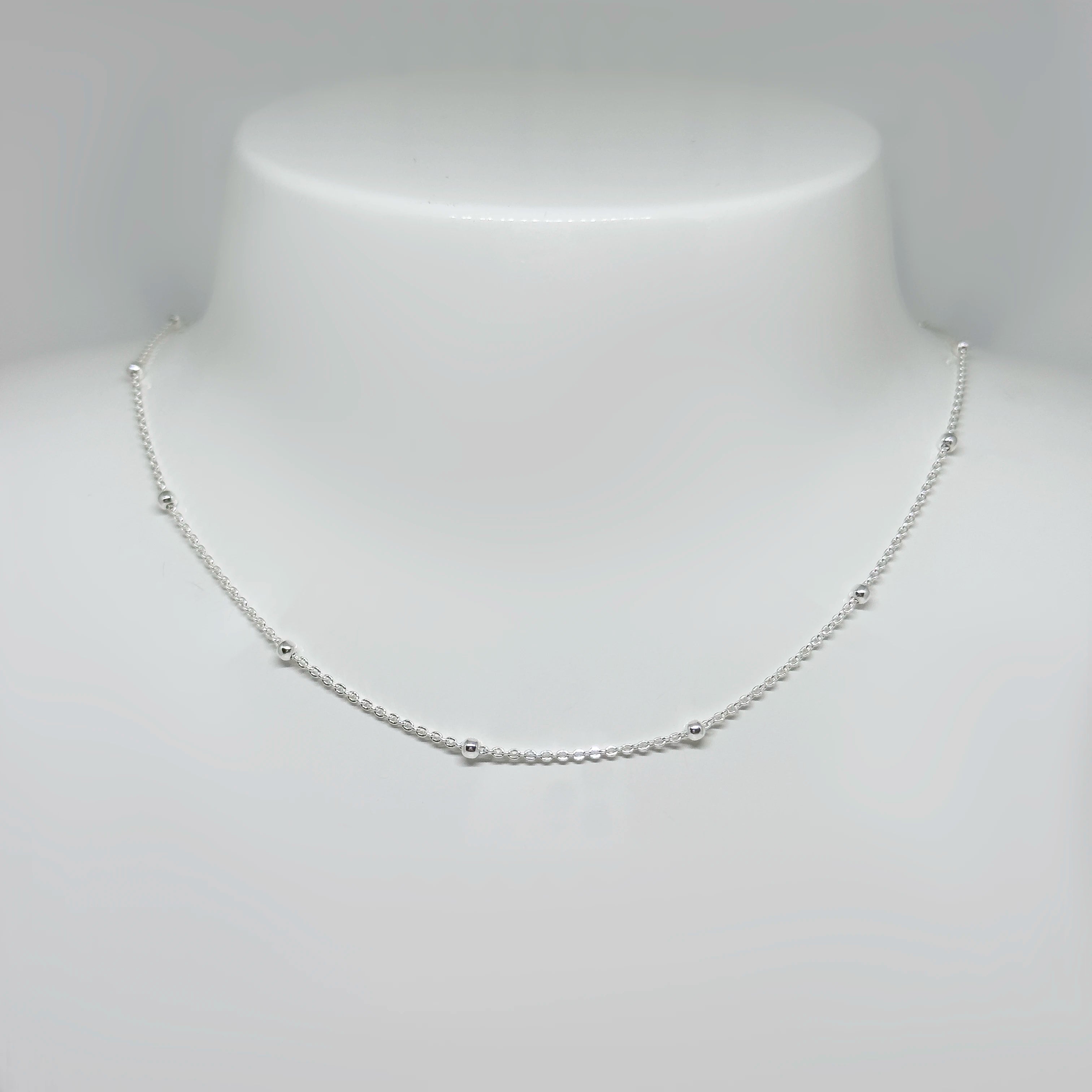 Hopeinen palloketju kuvattuna valkoisella korutelineellä