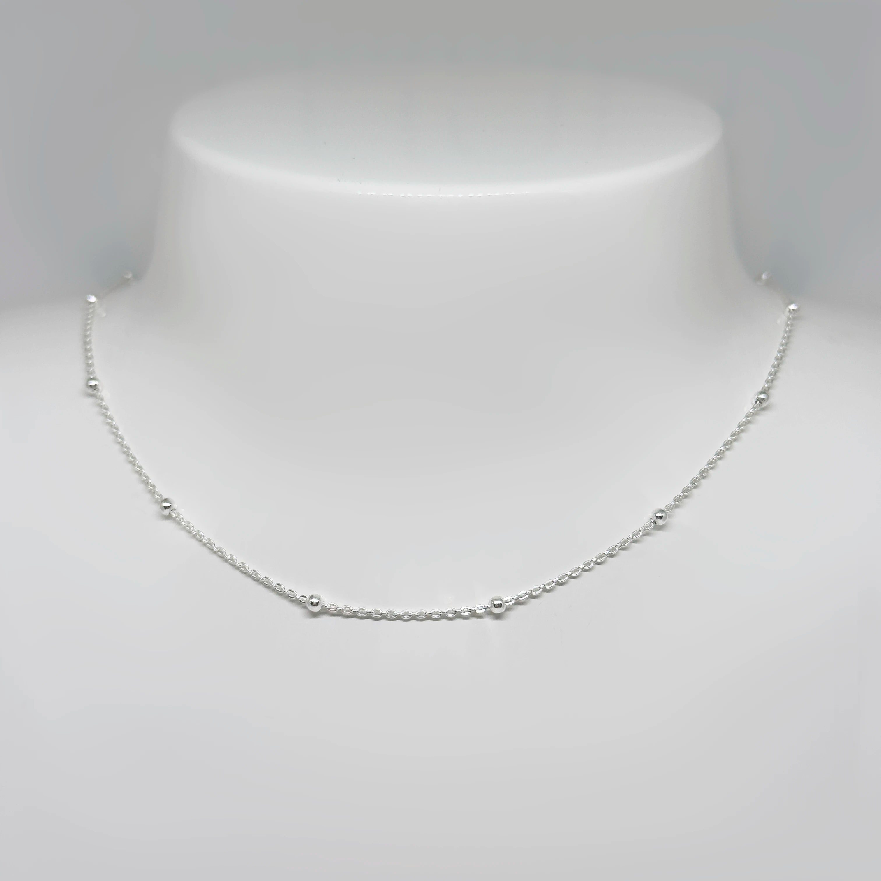 Hopeinen palloketju kuvattuna valkoisella korutelineellä