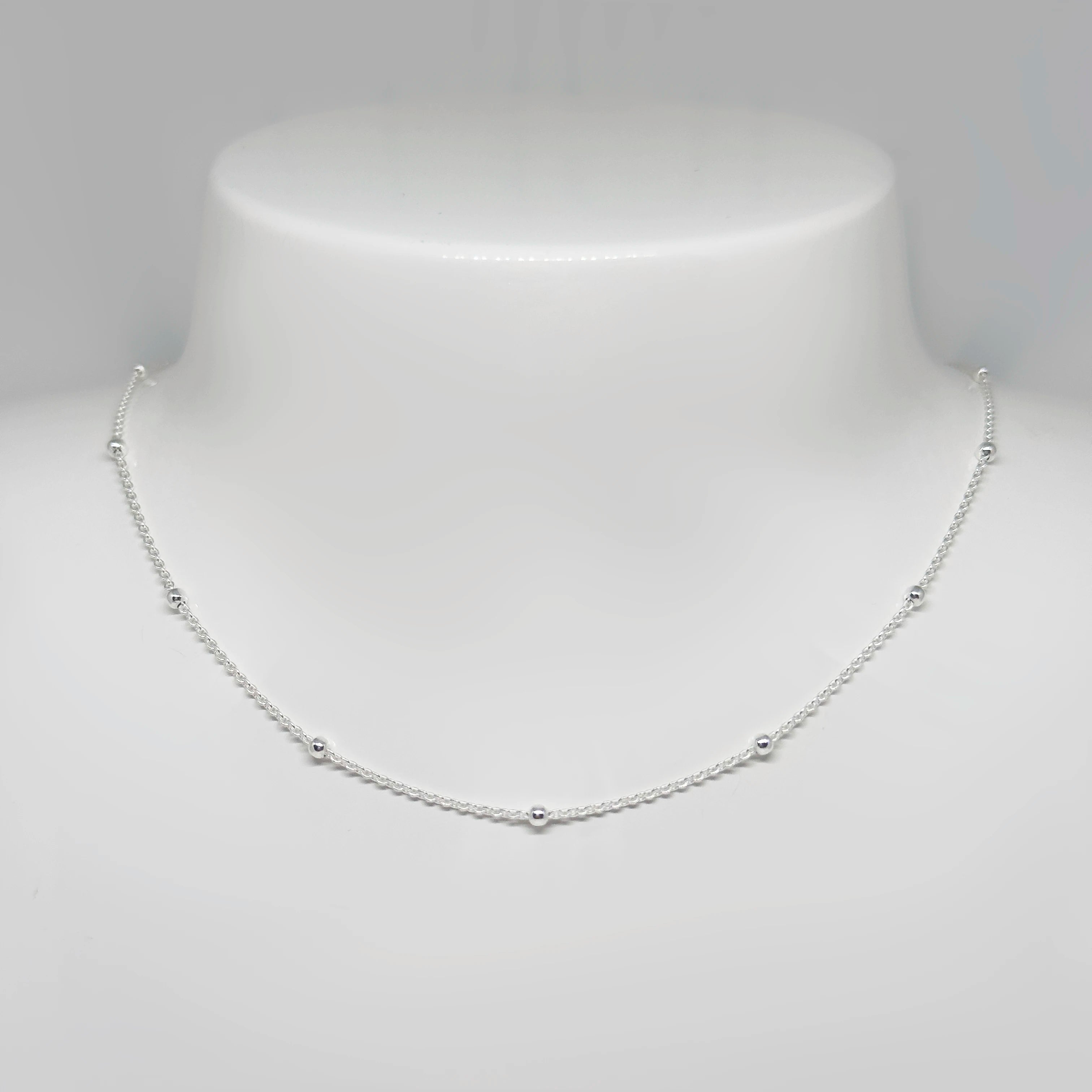 Hopeinen palloketju kuvattuna valkoisella korutelineellä