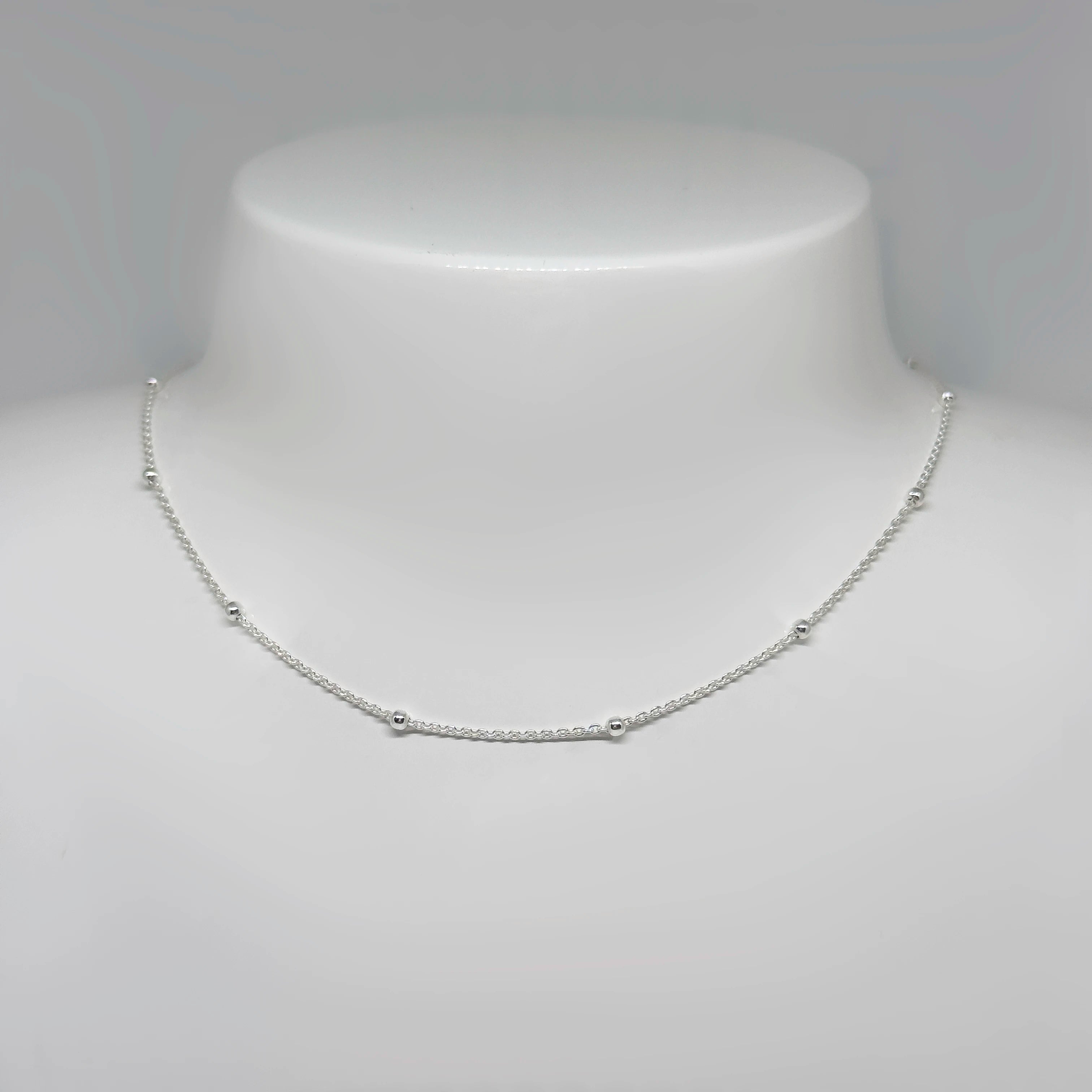 Hopeinen palloketju kuvattuna valkoisella korutelineellä