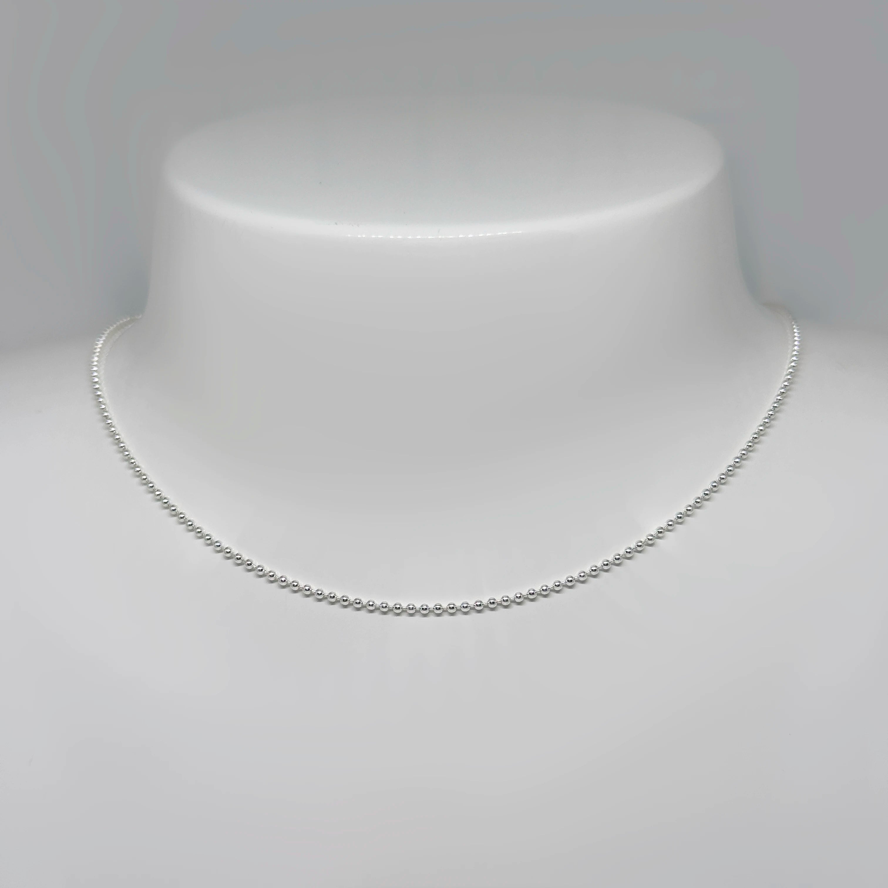 Hopeinen palloketju kuvattuna valkoisella korutelineellä