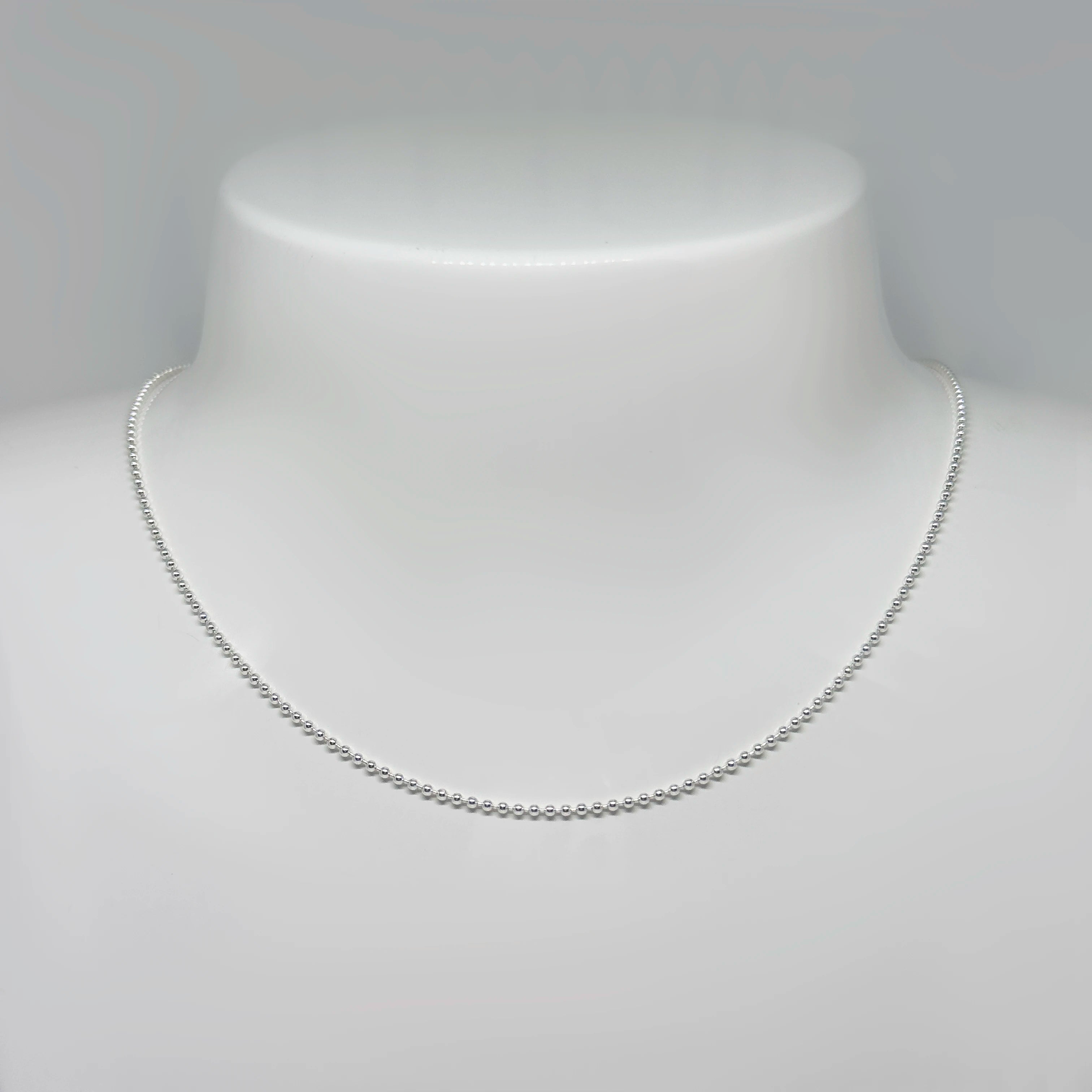 Hopeinen palloketju kuvattuna valkoisella korutelineellä