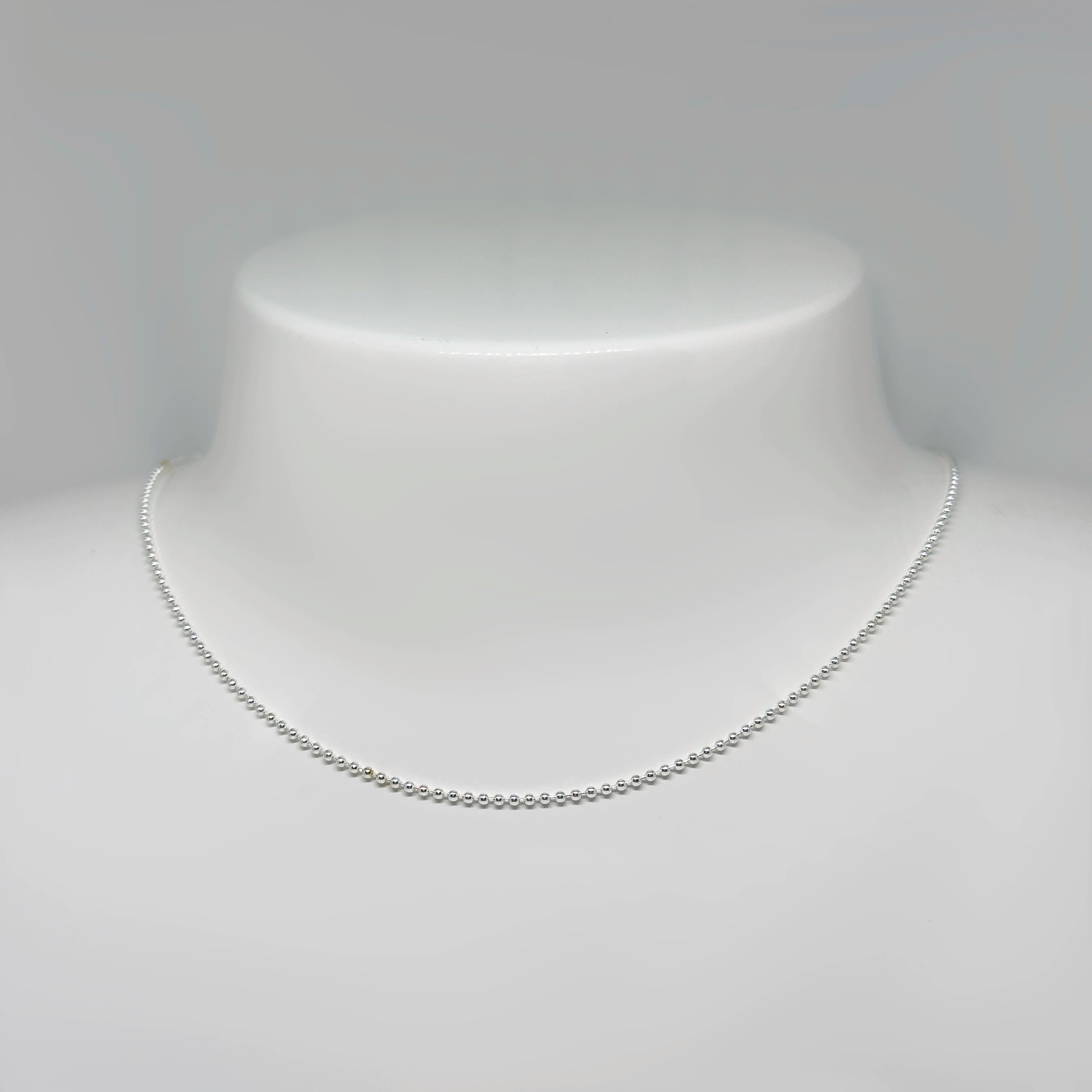 Hopeinen palloketju kuvattuna valkoisella korutelineellä