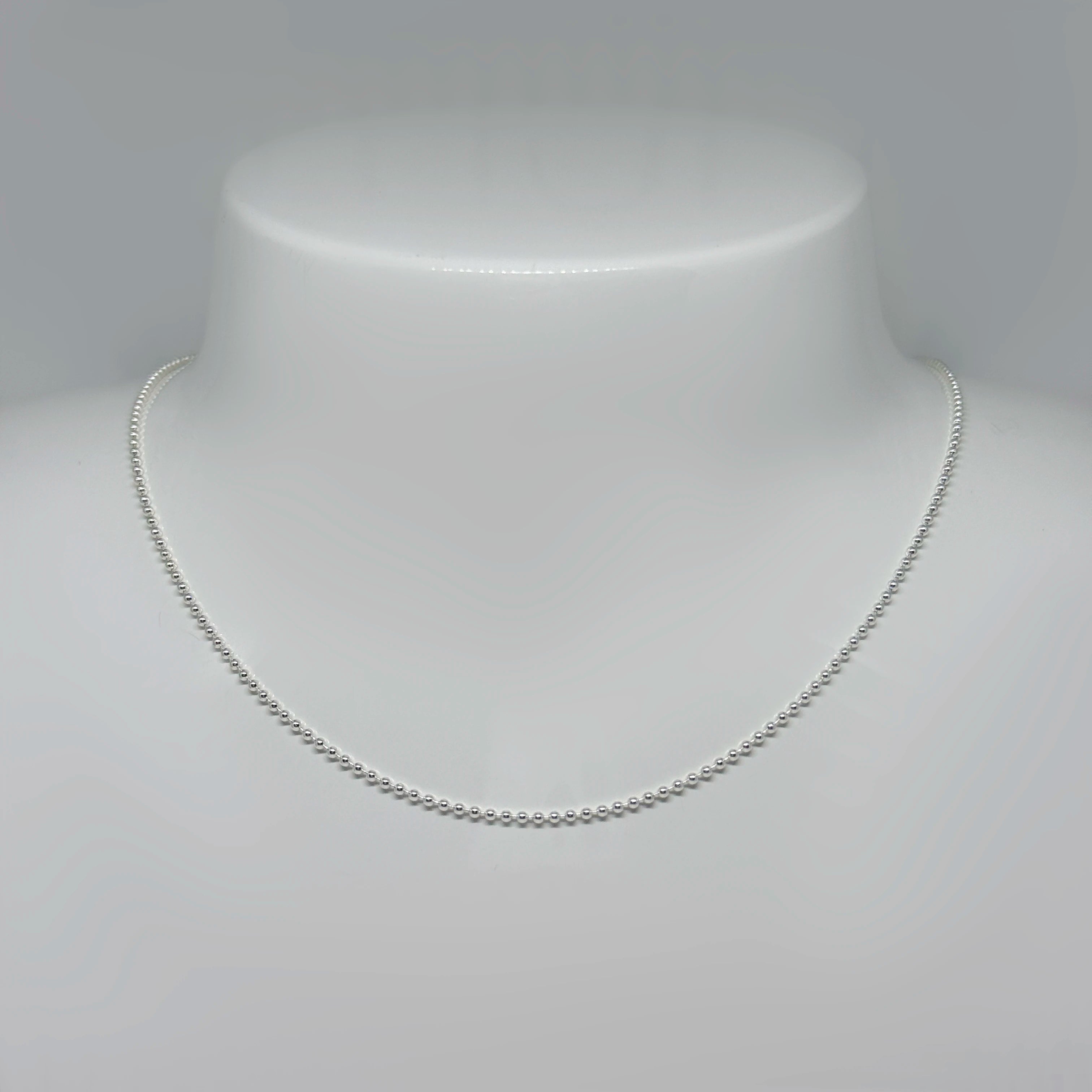 Hopeinen palloketju kuvattuna valkoisella korutelineellä