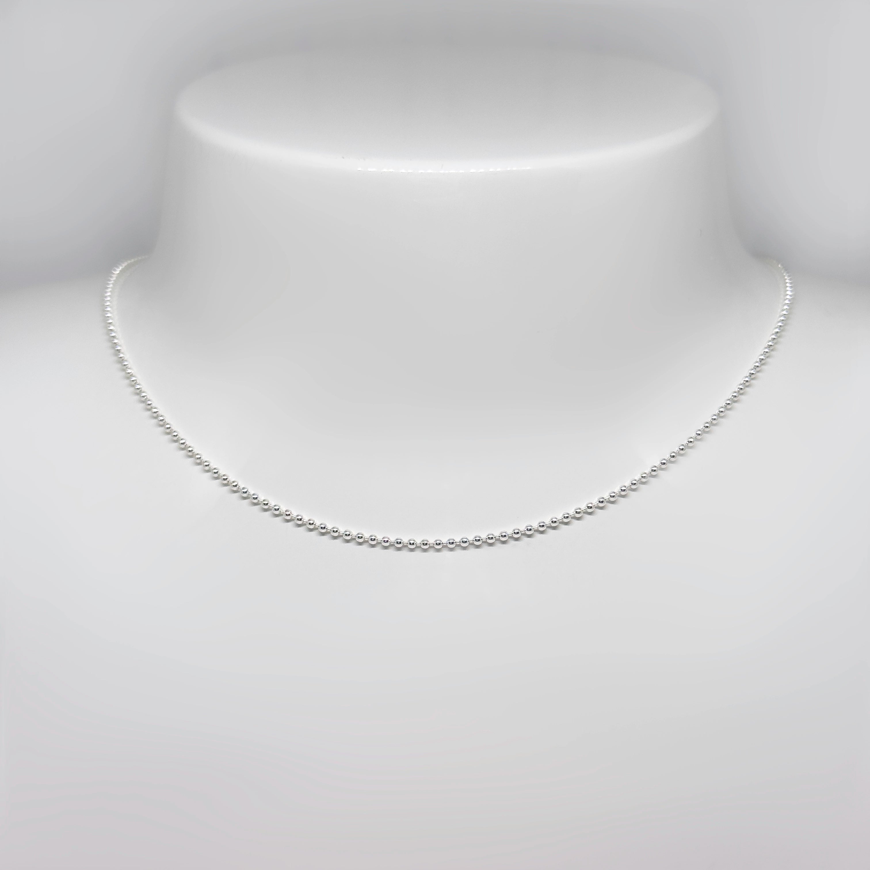 Hopeinen palloketju kuvattuna valkoisella korutelineellä