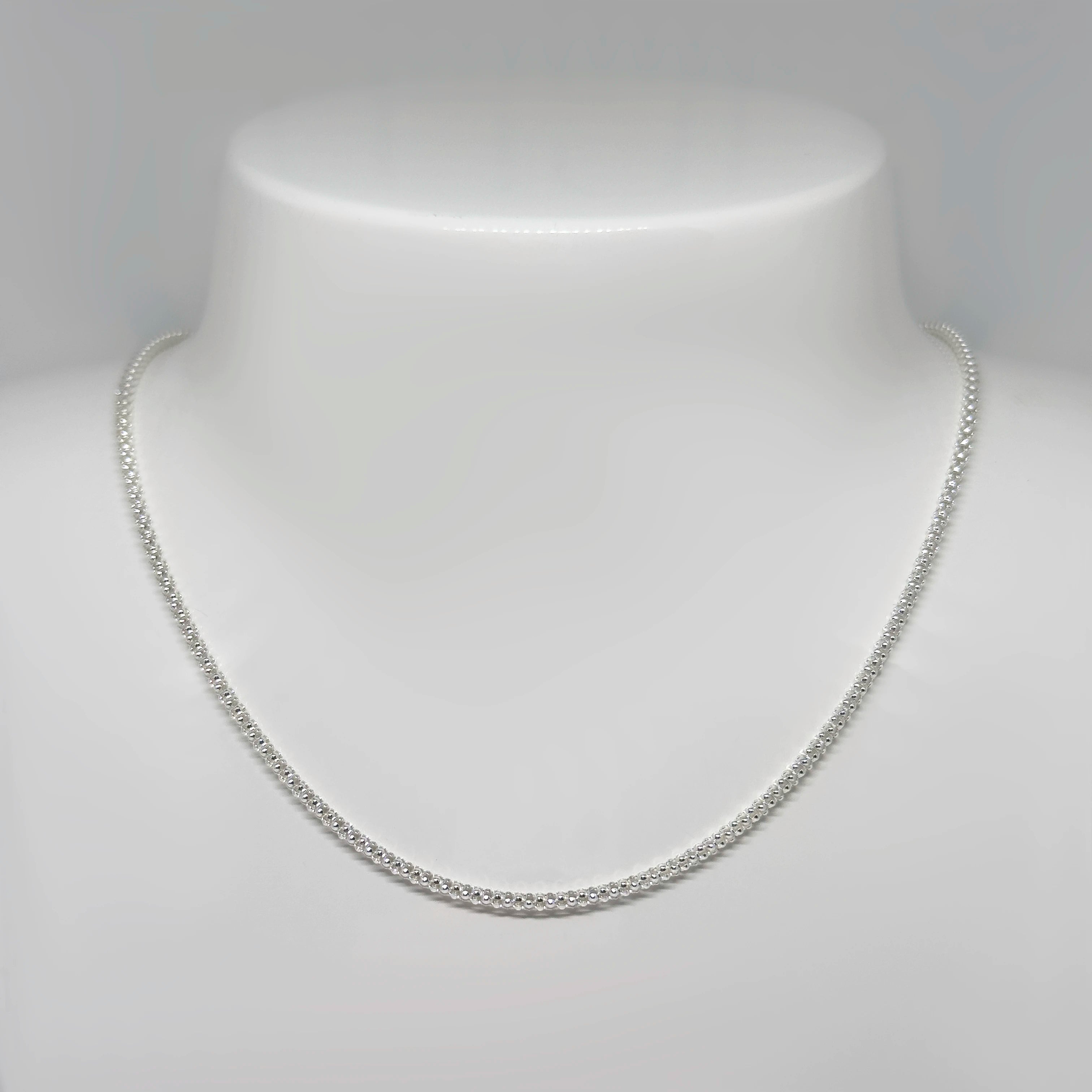 Hopeinen popcornketju kuvattuna valkoisella korutelineellä