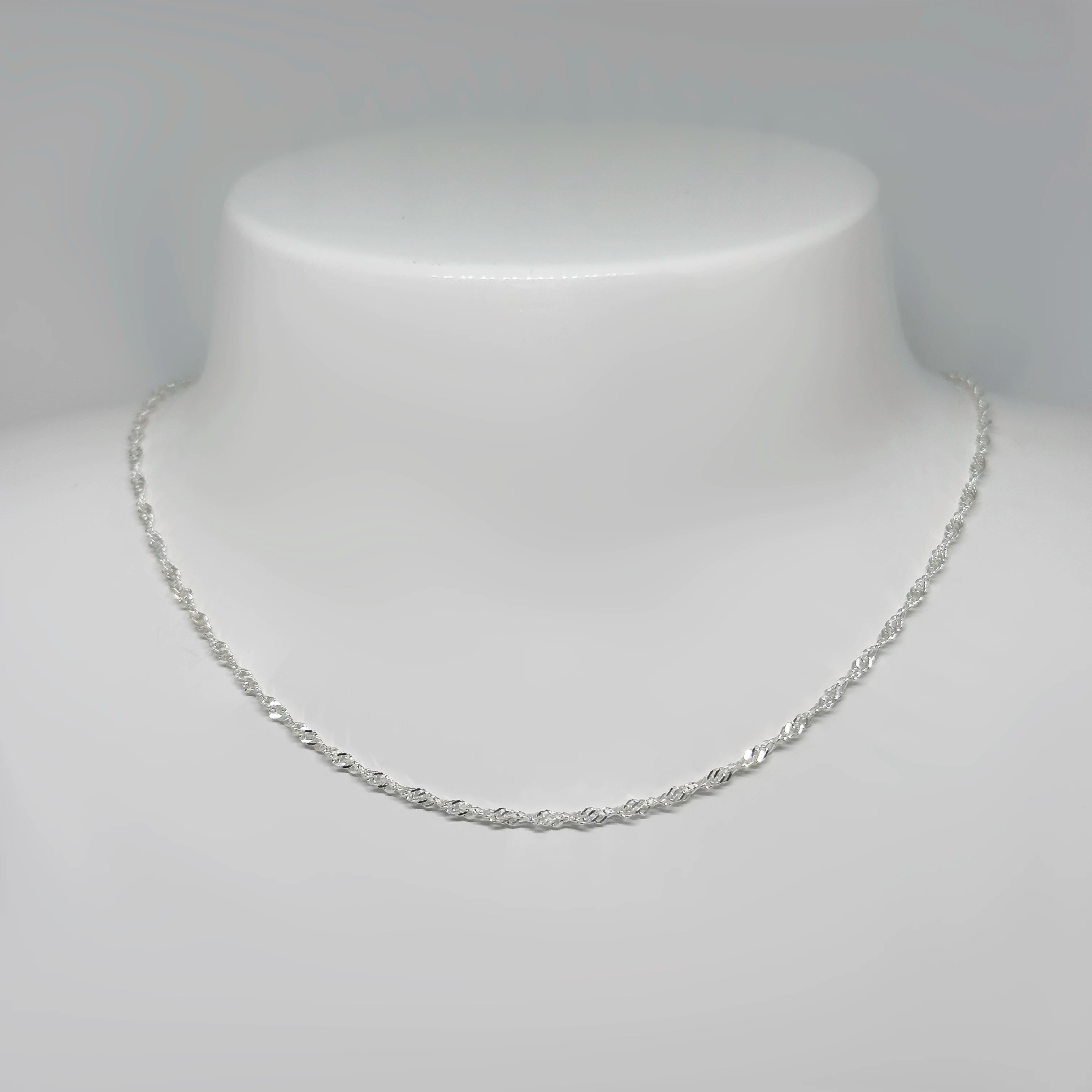 Hopeinen singaporeketju kuvattuna valkoisella korutelineellä