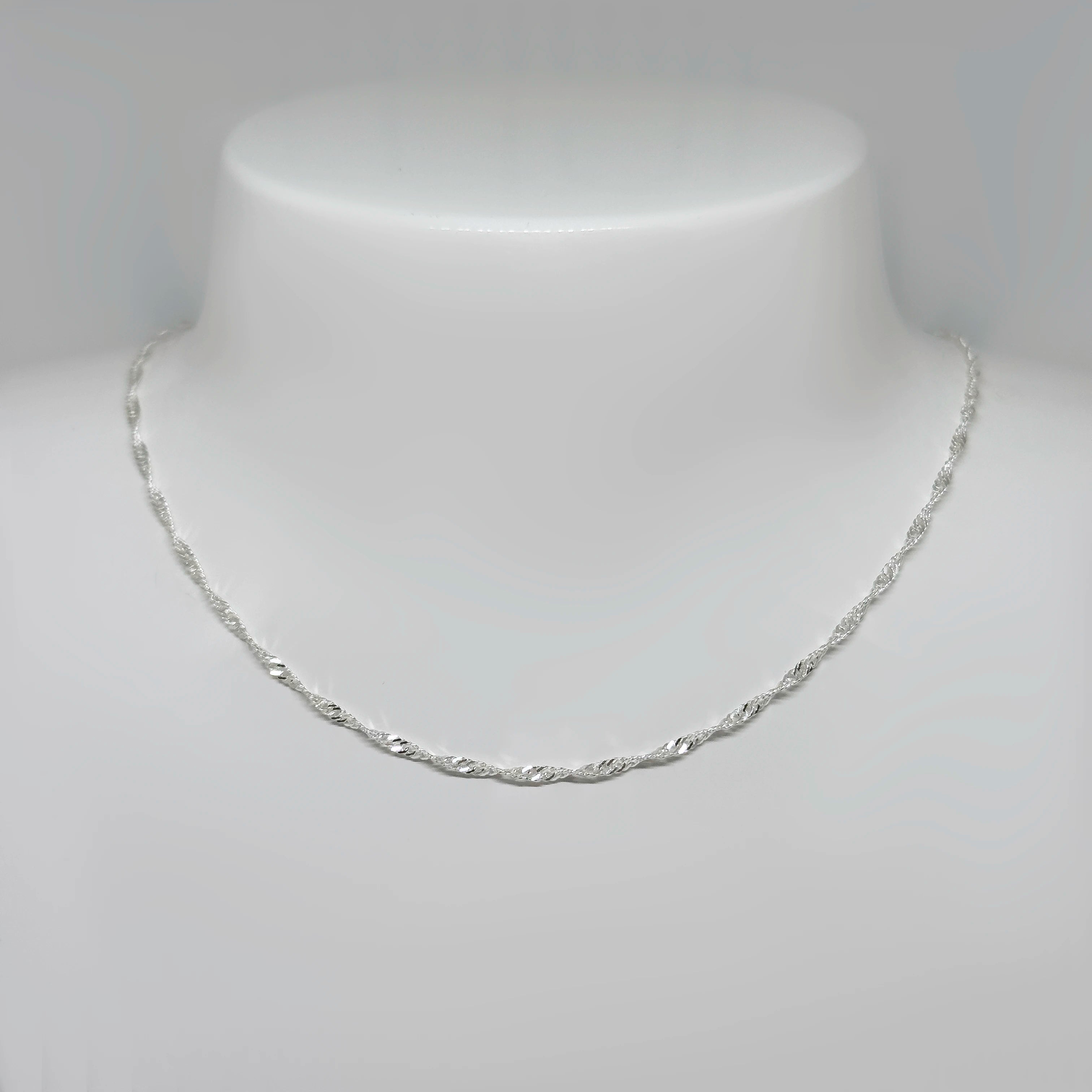 Hopeinen singaporeketju kuvattuna valkoisella korutelineellä