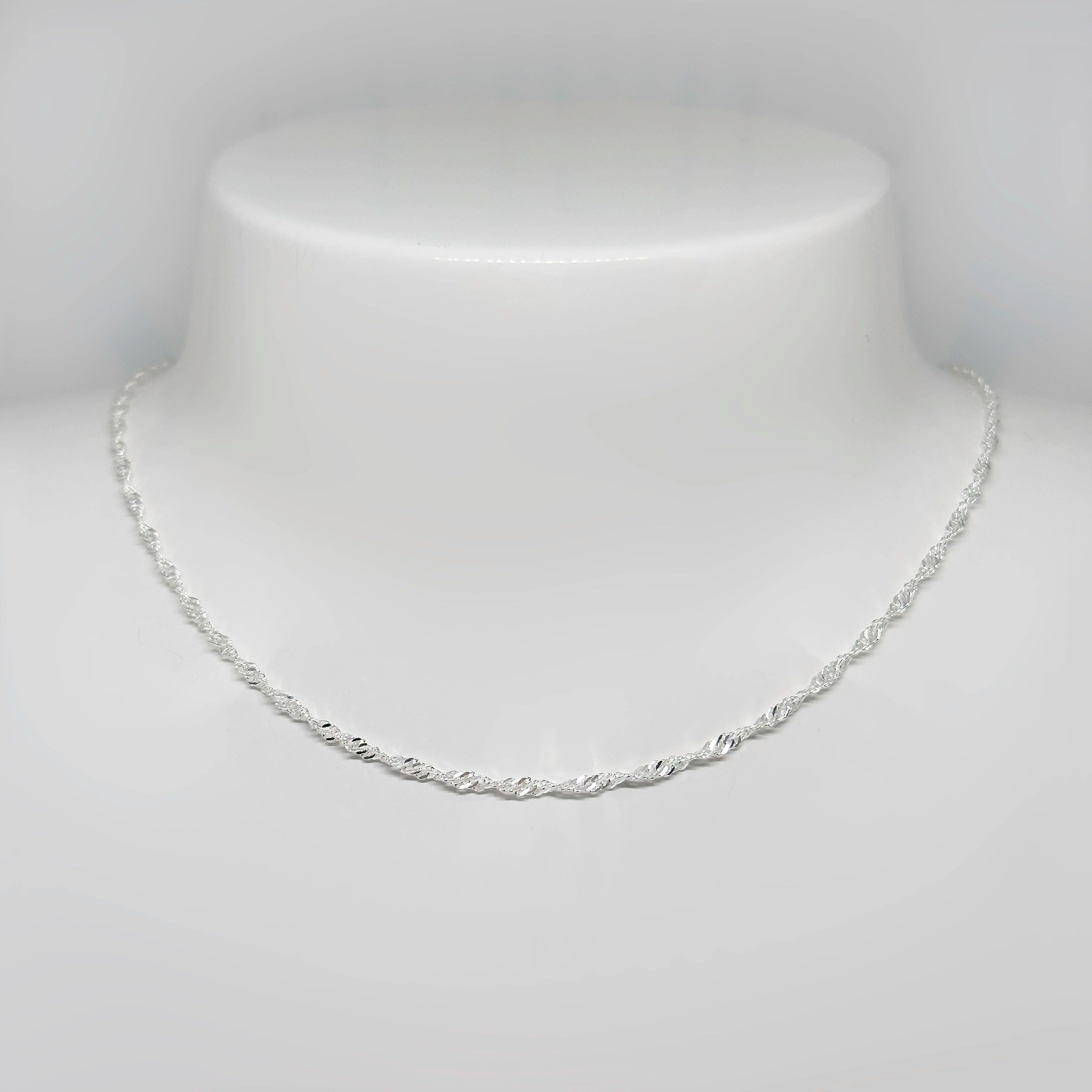 Hopeinen singaporeketju kuvattuna valkoisella korutelineellä