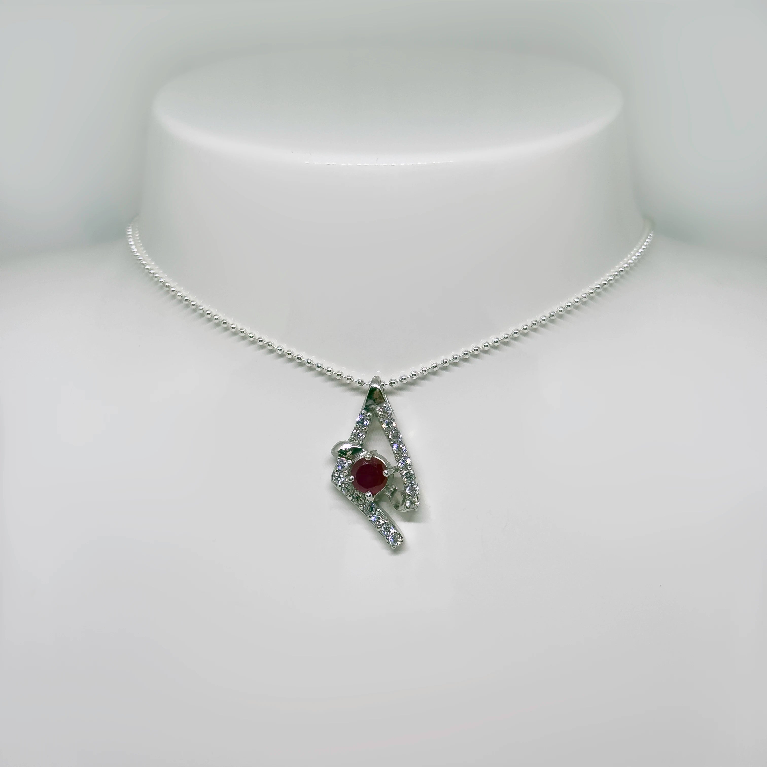 Hopeinen synteettinen rubiini zirkonia riipus kuvattuna valkoisella korutelineellä