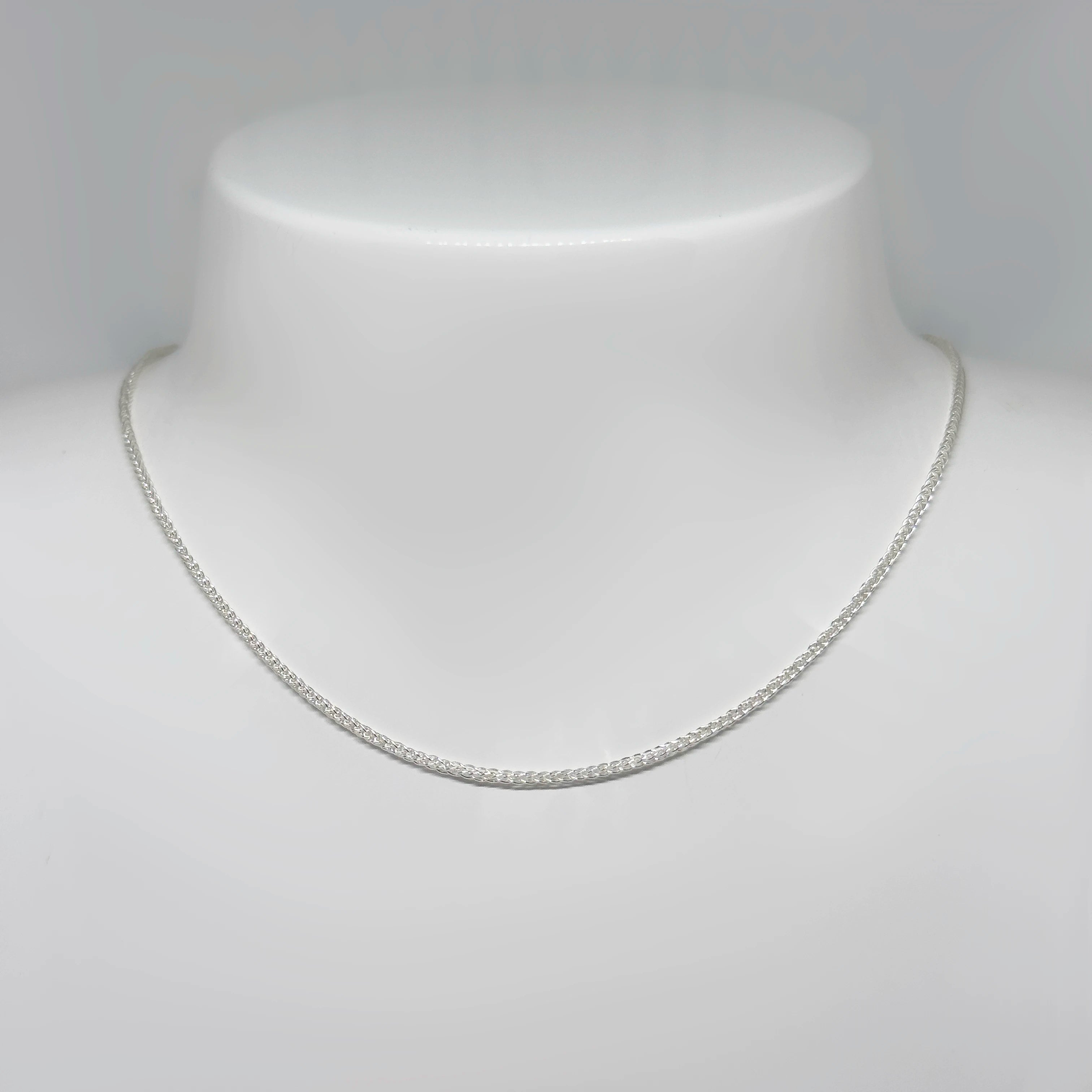 Hopeinen tähkäketju kuvattuna valkoisella korutelineellä