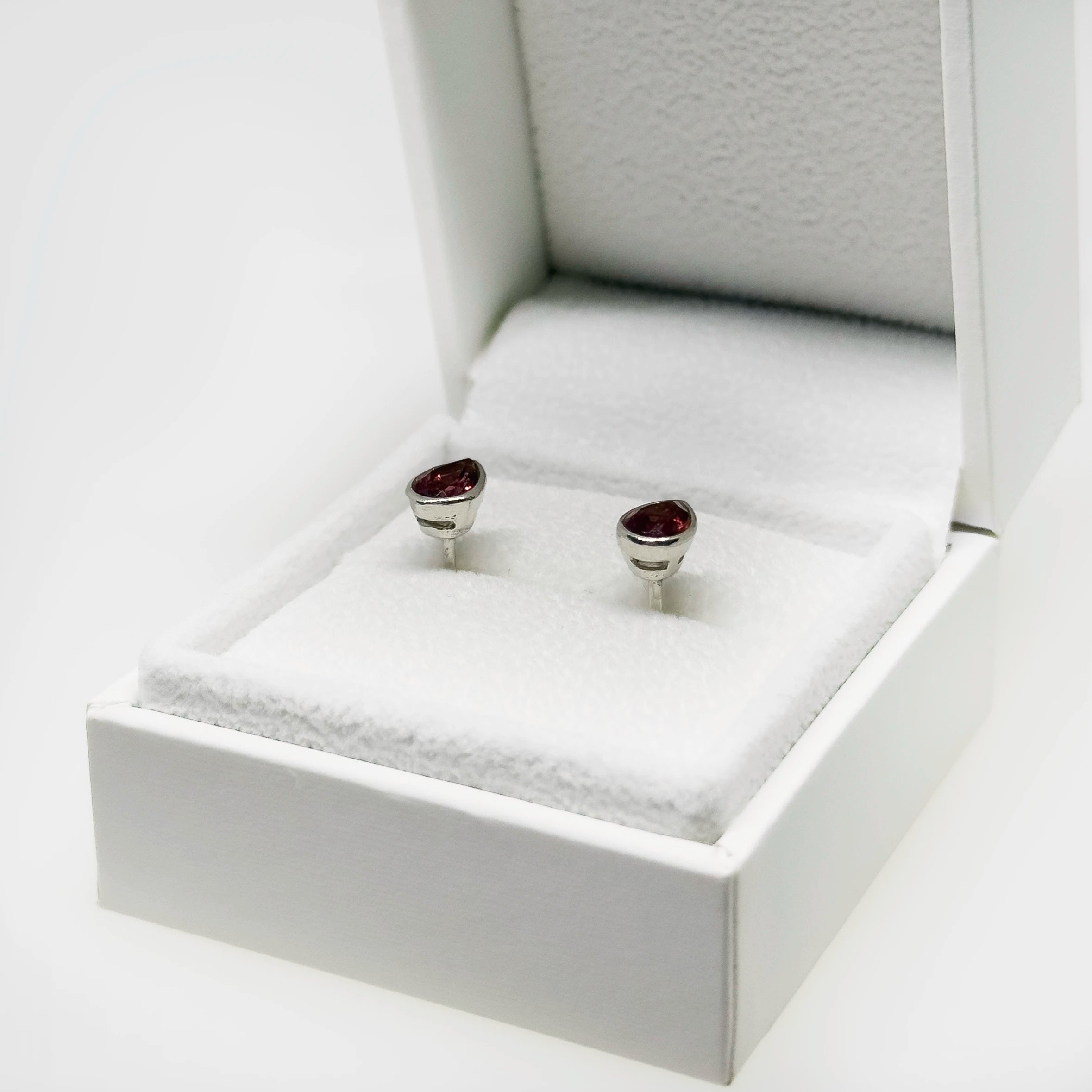 Hopeiset granaatti kyynel korvakorut kuvattuna valkoisella korutelineellä