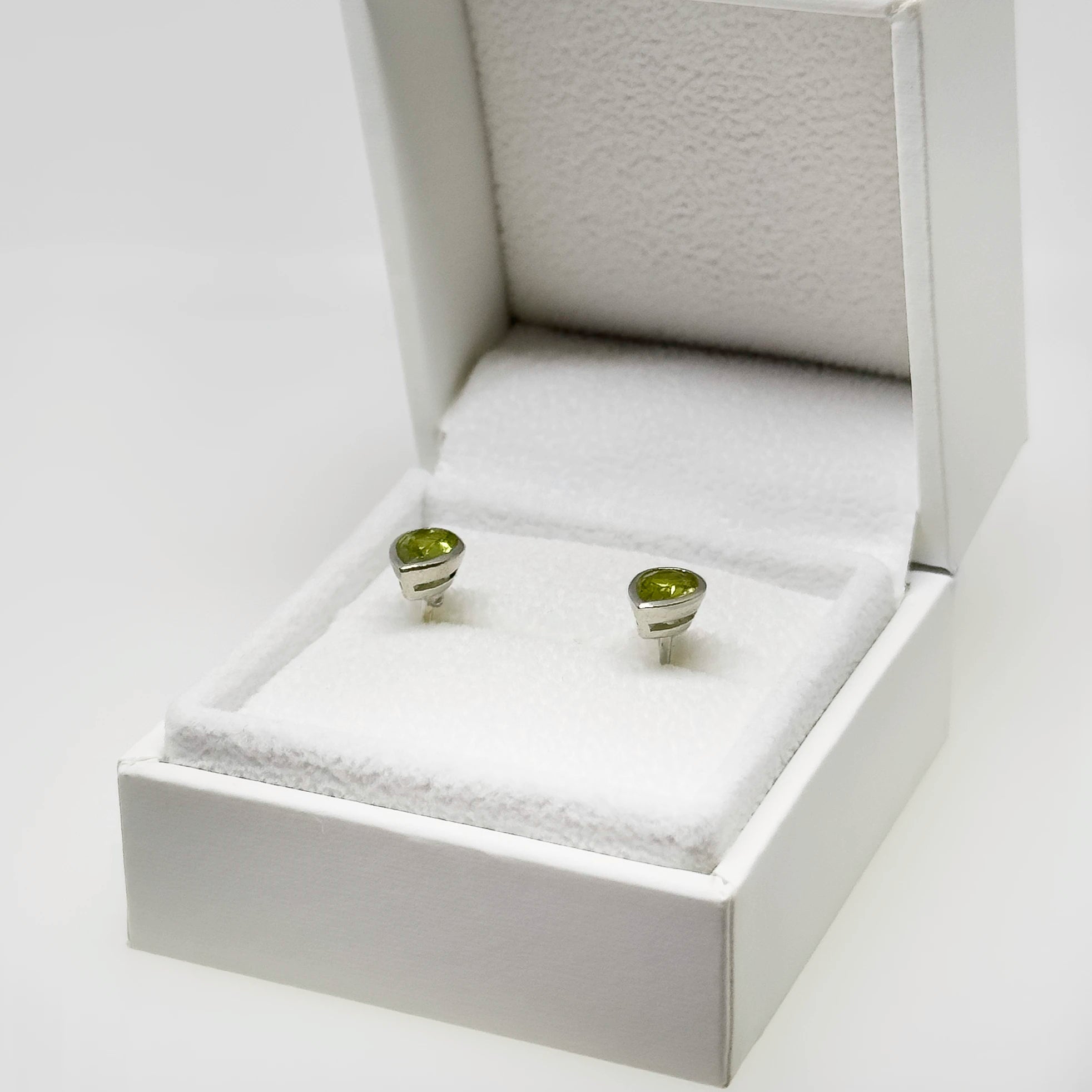 Hopeiset peridootti kyynel korvakorut kuvattuna valkoisella korutelineellä