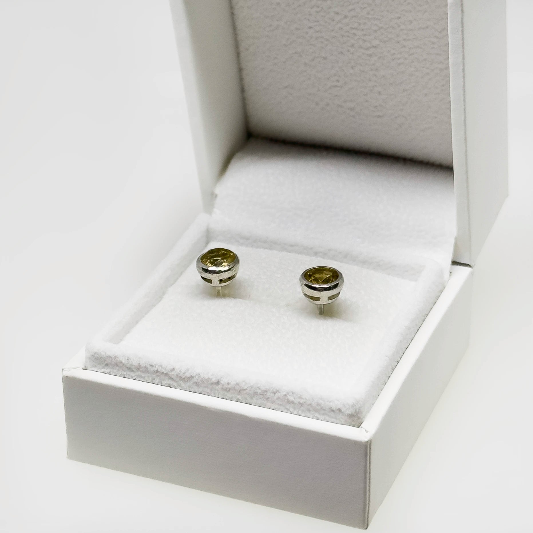 Hopeiset sitriini korvakorut kuvattuna valkoisella korutelineellä