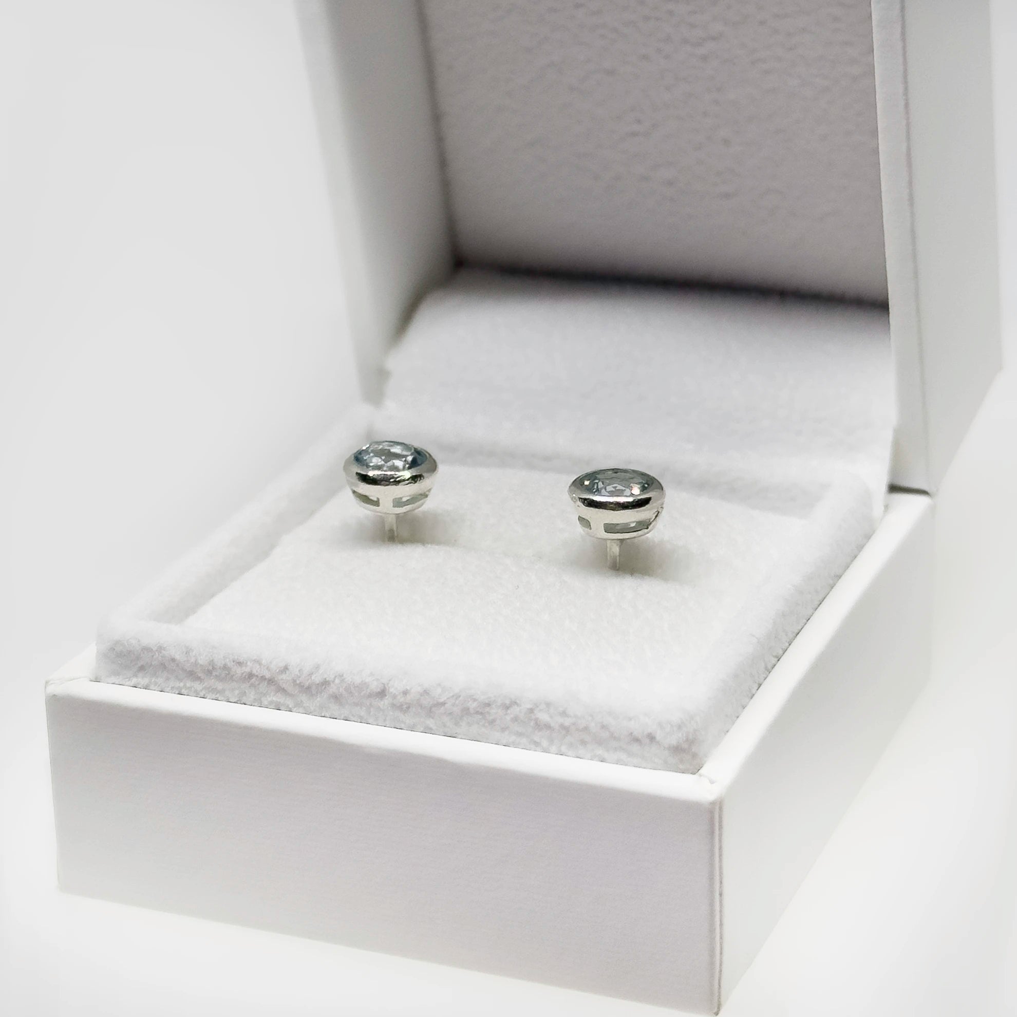 Hopeiset topaasi korvakorut kuvattuna valkoisella korutelineellä