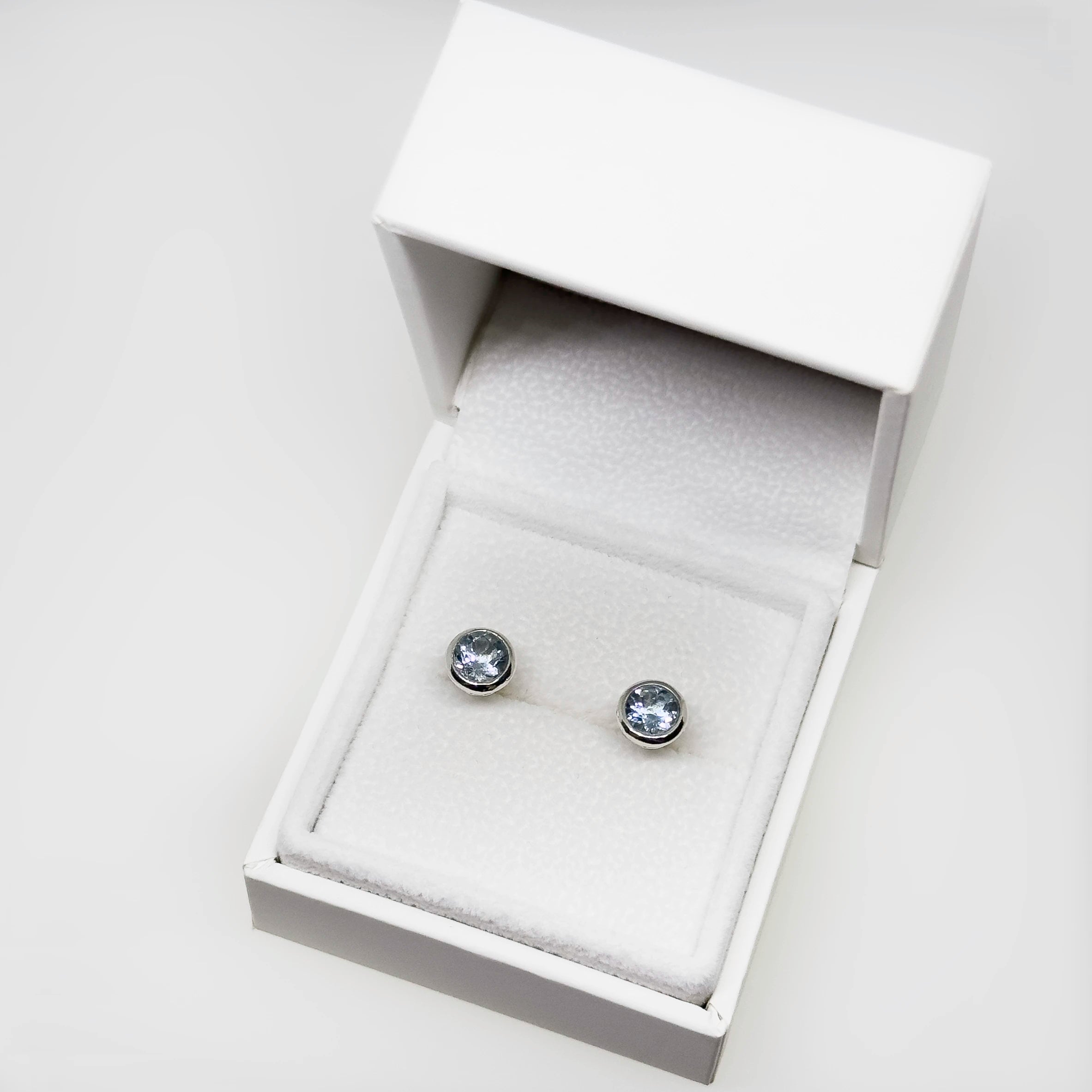 Hopeiset topaasi korvakorut kuvattuna valkoisella korutelineellä