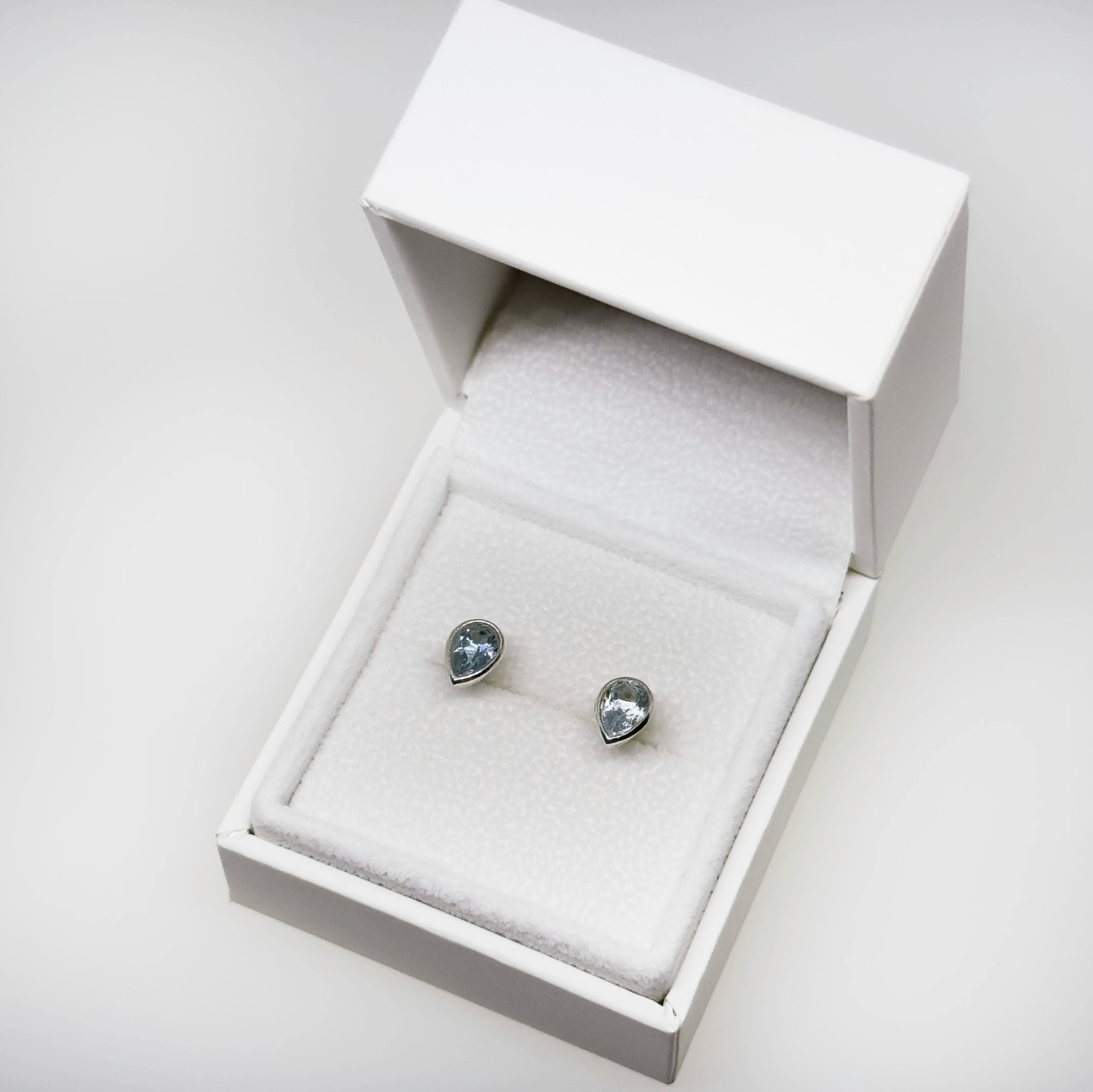 Hopeiset topaasi kyynel korvakorut kuvattuna valkoisella korutelineellä